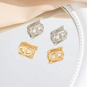 Macro view of gold and silver hollow chain link earrings on a pearl mirror tray