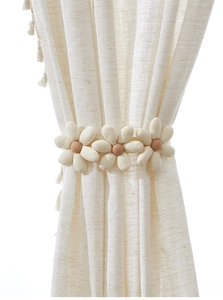 Close-up of handmade jute flower tieback with cream petals on textured curtain