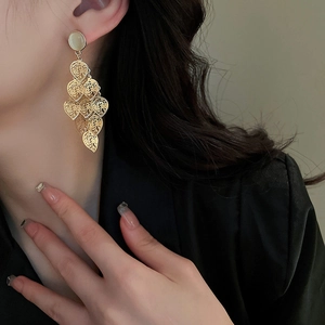 Golden leaf tassel earrings with cat eye stone worn by a model to show length