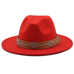 Close-up of red wool fedora hat featuring a brown leather band with silver floral rivets
