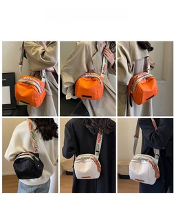 Detail view of stylish shell cross-body bags in orange, black, and white with wide straps