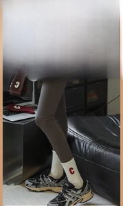 Détail de chaussettes blanches côtelées avec broderie C rouge et legging gris foncé