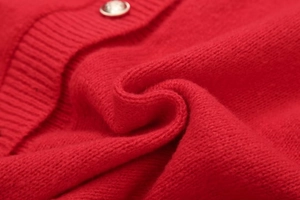 Gros plan sur un cardigan en maille rouge avec texture douce et bouton métal argenté