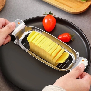 Stainless steel butter cheese slicer with metal wire cutting slices on a black plate
