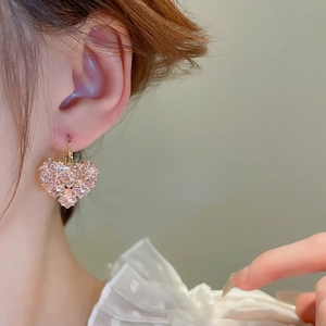 Close-up of pink heart-shaped crystal earrings with gold plating on female model