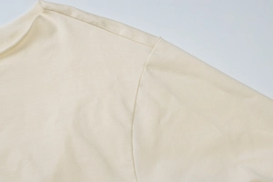 Detail of crew neck and shoulder stitching on beige knitted long sleeve cropped top
