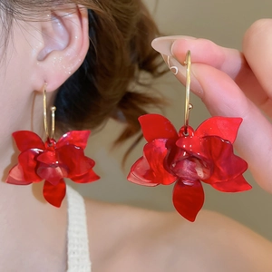 Detail of red 3D resin flower earrings with golden hoops worn by a model