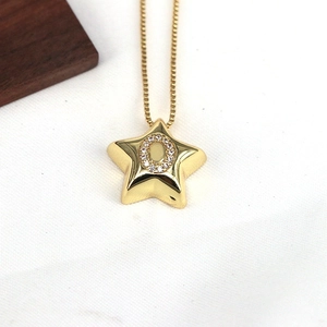 Macro shot of gold star pendant with zircon-inlaid letter O on a fine snake chain