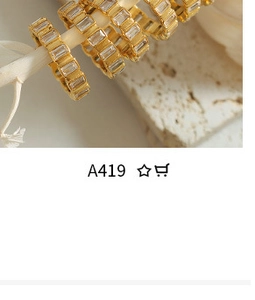 Detailed macro view of gold hoop earrings with clear rectangular zircons on stone surface