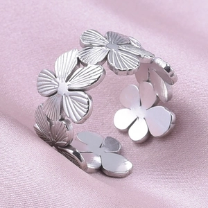 Detailed close-up of floral pattern ring with adjustable band on pink satin background