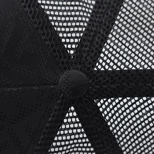 Close-up of black mesh fabric and top button on a breathable trucker baseball cap