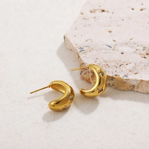 Close-up of 18K gold-plated C-shaped hoop earrings with star engravings and zircons