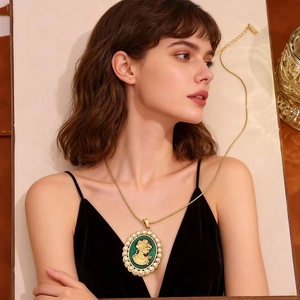 Elegant gold-plated portrait pendant necklace with pearls on a model wearing warm tones