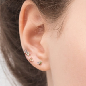 Close-up of model wearing starry blue zircon and candy-colored small gold stud earrings set
