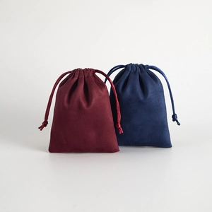 Detailed close-up of velvet drawstring jewelry pouches in wine red and navy blue colors
