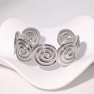 Bracelet jonc ouvert en acier inoxydable poli argenté sur un socle blanc artistique