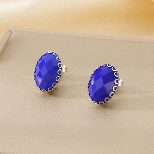 Detailed shot of oval blue faceted glass studs with silver floral basket setting