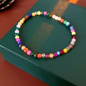 Macro detail of colorful gemstone beaded bracelet on a dark green textured jewelry box