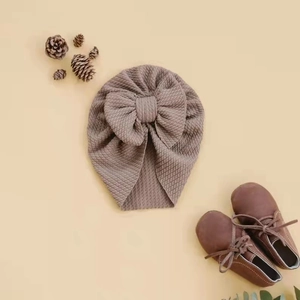 Detailed flat lay of brown waffle knit baby turban hat with a large decorative bow