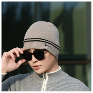 Close-up of knit texture and black FBQE label on light brown winter beanie hat