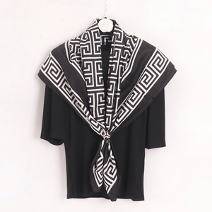 Detail of Greek key pattern silk scarf styled with a scarf clip on black top