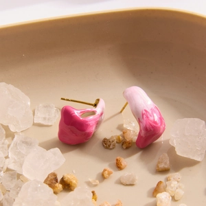 Detail of 18K gold stainless steel pink enamel stud earrings on a crystal tray