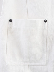 Detail of white denim vest featuring a square patch pocket and metallic rivet studs