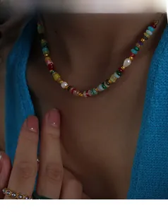 Close-up of bohemian colorful beaded necklace with freshwater pearls and gold accents on a model