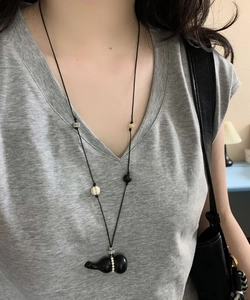 Close-up of wax rope necklace featuring a wooden gourd pendant and pearl bead accents