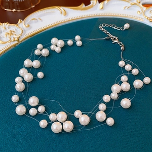 Macro detail of multi-layer staggered pearl necklace with silver lobster clasp on blue tray