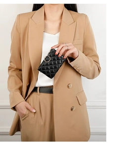 Close-up of black quilted leather coin purse with golden ring zipper held by a model