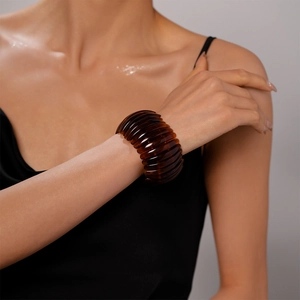 Détail macro d'un bracelet manchette en acrylique ambre sur le poignet d'un mannequin