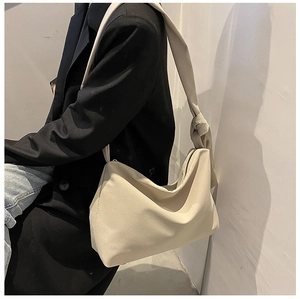 Close-up of beige canvas crossbody bag with a knotted strap detail on a model