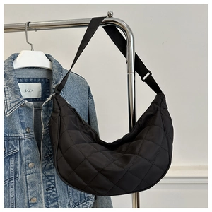 Détail de la bandoulière réglable sur un sac demi-lune en nylon noir avec matelassage