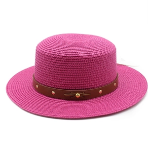 Détail d'un chapeau de paille rose avec ruban en cuir clouté et texture tressée