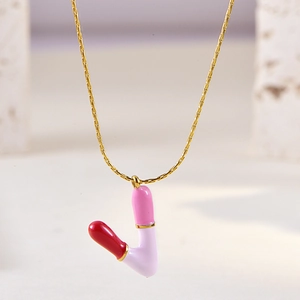 Macro shot of V-shaped gold chain pendant with pink and purple enamel finish