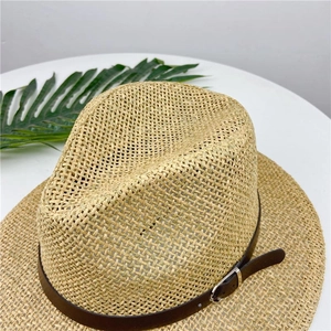 Detailed close-up of straw fedora hat with brown leather strap and metal buckle