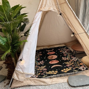 Detail of moon phase woven blanket inside a teepee tent with bohemian fringe accents