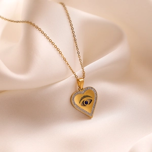 Golden heart pendant necklace with blue evil eye and zircons on beige silk background