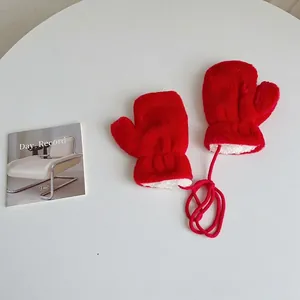 Detail of red plush baby mittens with neck string and warm fleece lining for winter