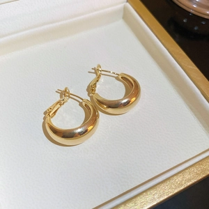 Close-up of golden geometric hoop earrings with polished finish in a white jewelry box
