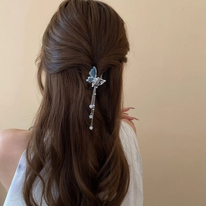 Détail d'une pince à cheveux papillon bleu avec glands en perles sur une coiffure