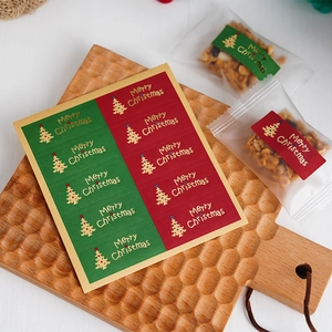 Christmas tree gift seal stickers in red and green with gold foil on a wood tray