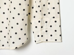 Detailed close-up of stitching on beige polka dot shirt cuff and hemline curvature