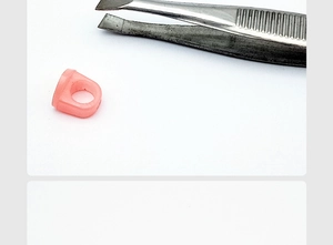 Detail of pink silicone lash application ring being handled with metal tweezers