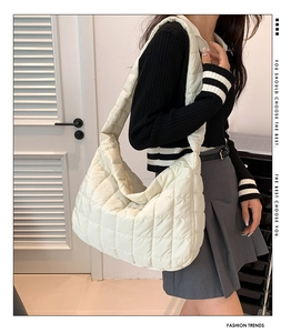 Detailed side view of white quilted padded tote bag with wide shoulder strap