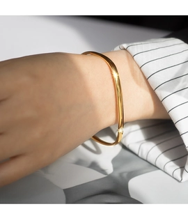 Detailed view of a gold square titanium steel bangle with micro-set zircon on woman's wrist