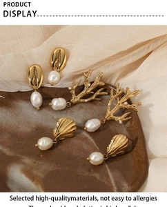 Detailed view of golden ocean-themed shell and pearl earrings on ceramic tray