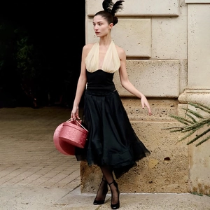 Dettaglio del top beige a fascia con corsetto nero e borsa rosa in un look elegante