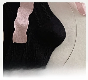 Detail of a reinforced heel on black lolita socks with pink wavy trim and knit texture